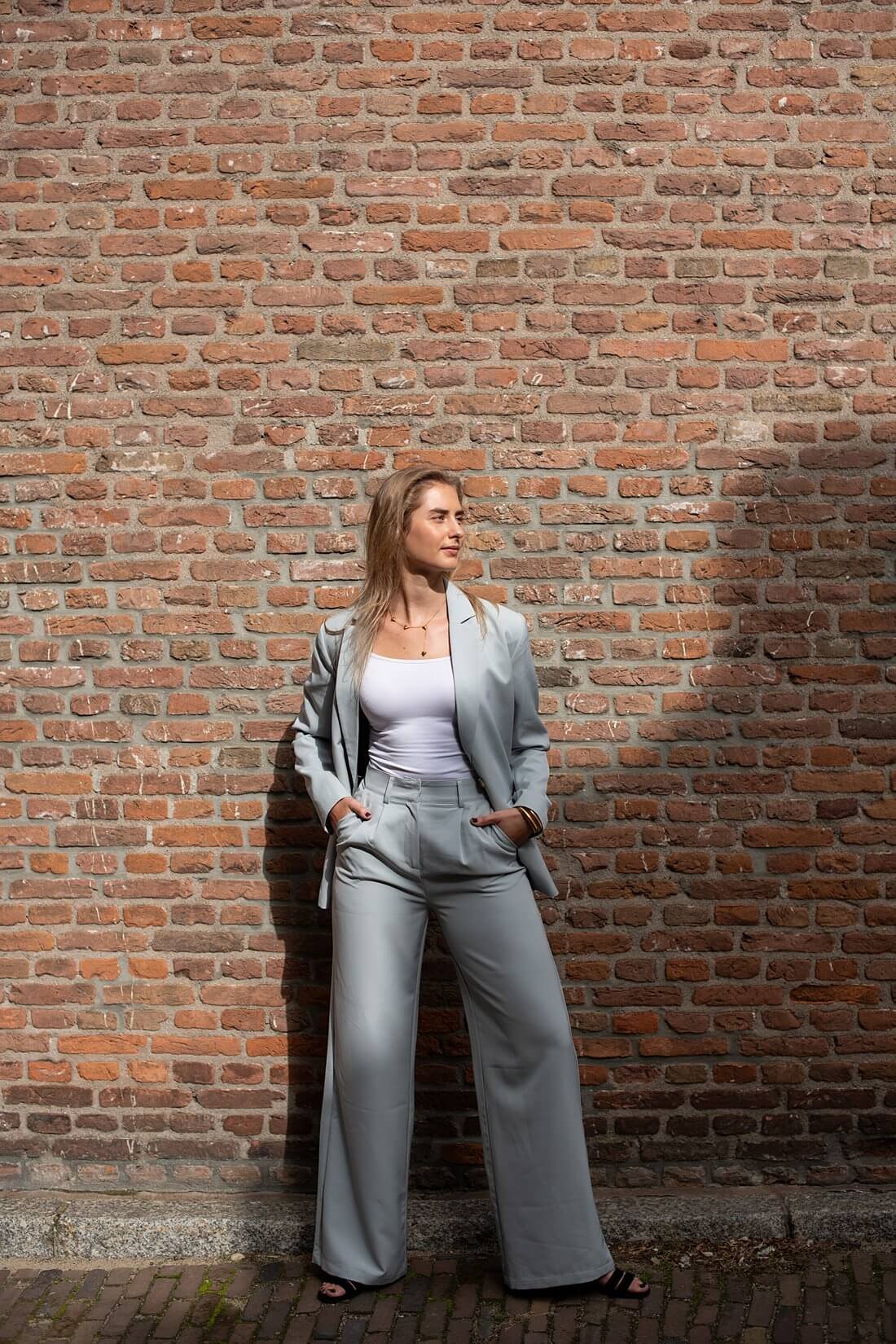 Sarah in een lichtgrijs pak gefotografeerd met achtergrondruimte bij de Stevenskerk.