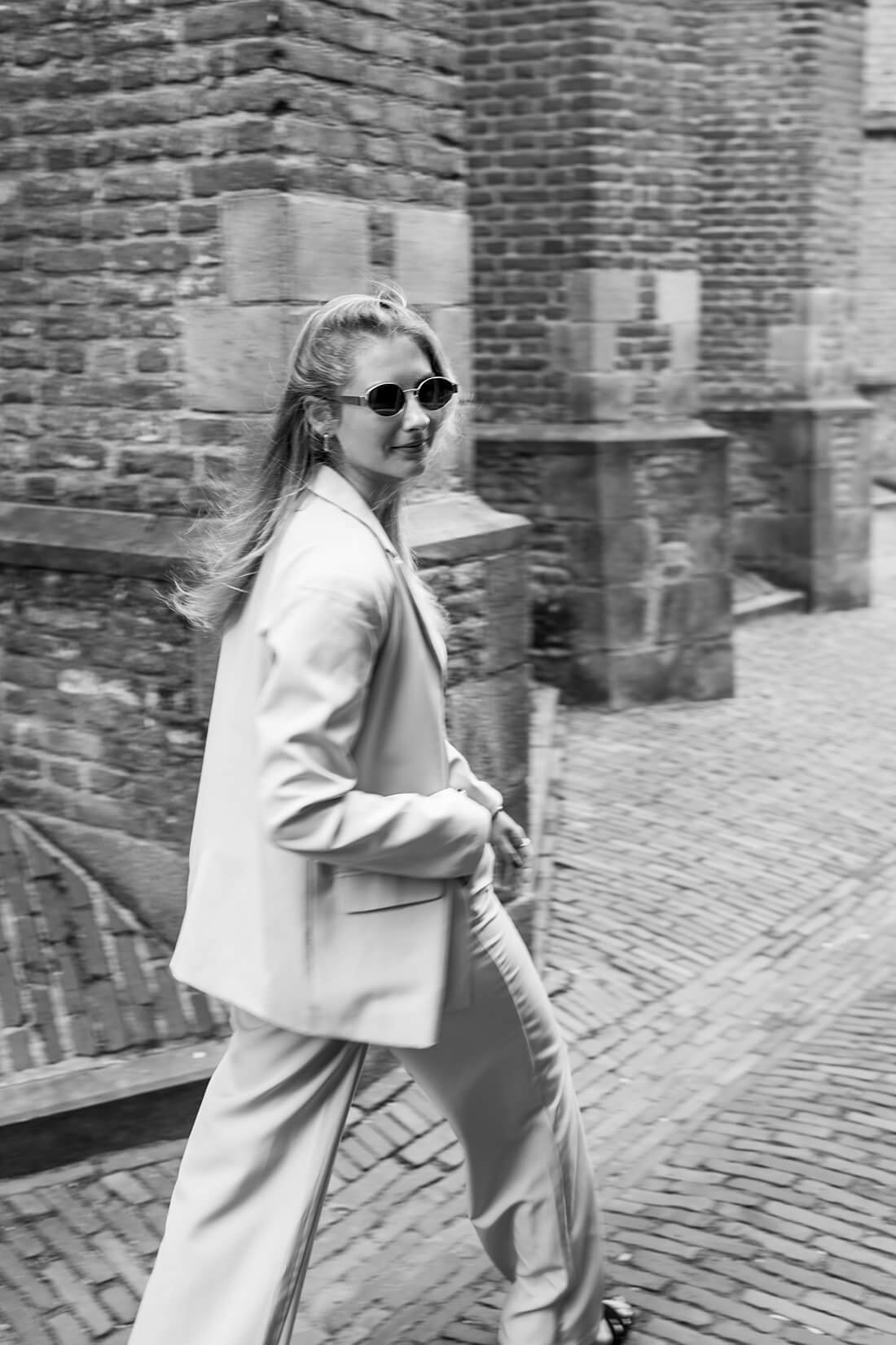 Zwart-wit high-fashion portret van onderneemster in lichtgrijs pak.