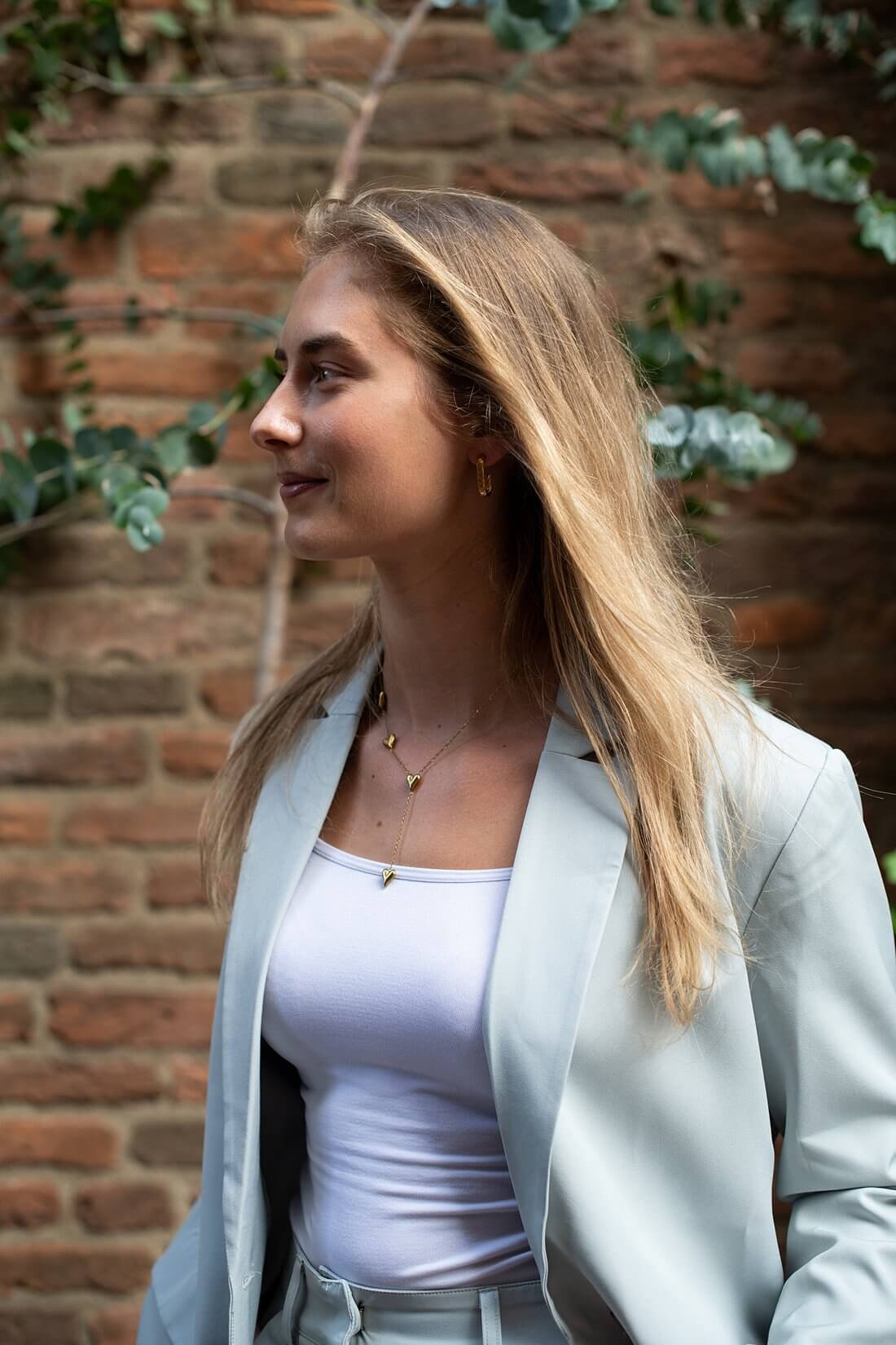 Zijprofiel portret van Sarah in een lichtgrijs pak in het centrum van Nijmegen.
