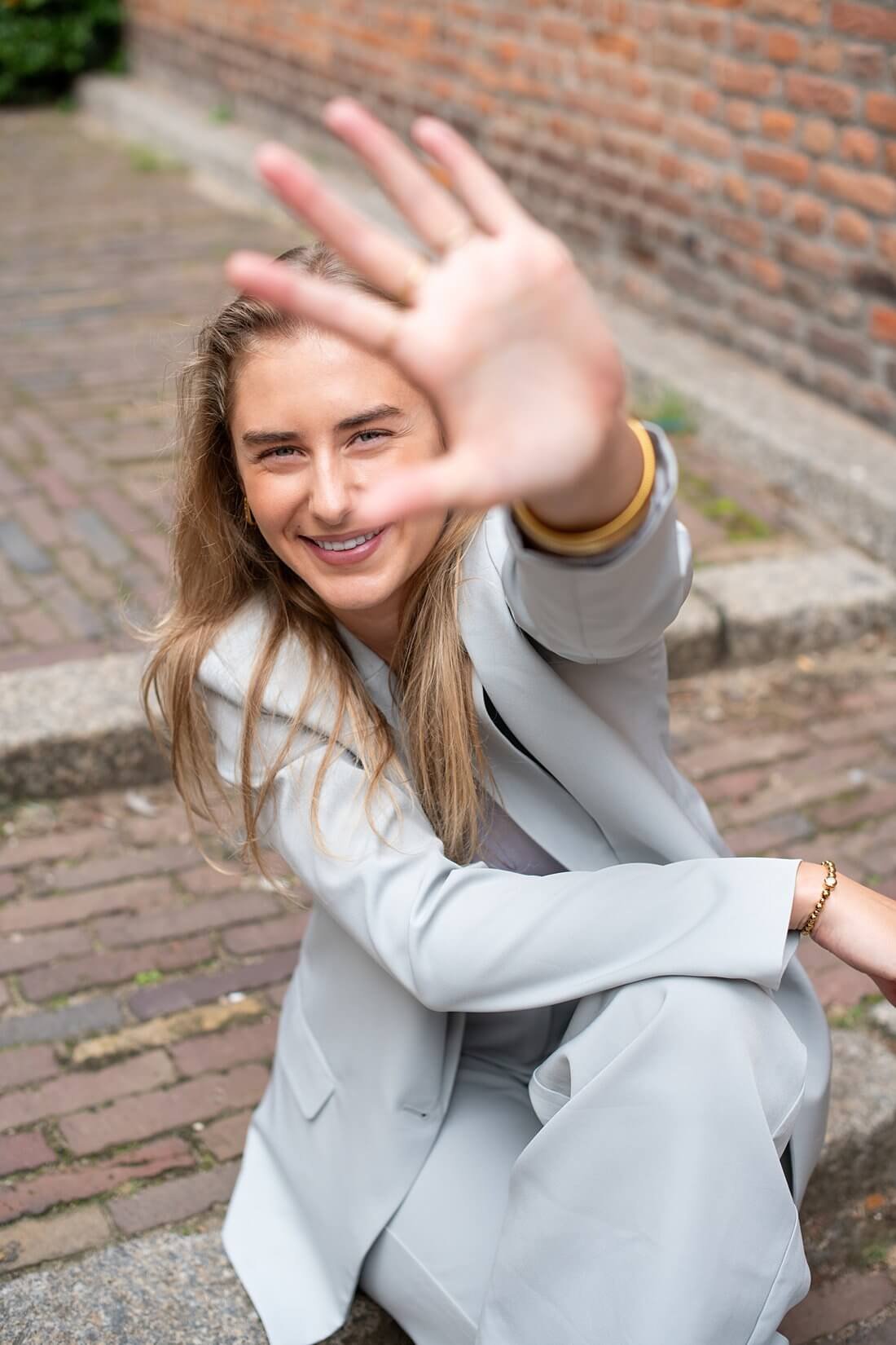 Spontaan lachende vrouw in lichtgrijs pak gefotografeerd bij de Stevenskerk Nijmegen.