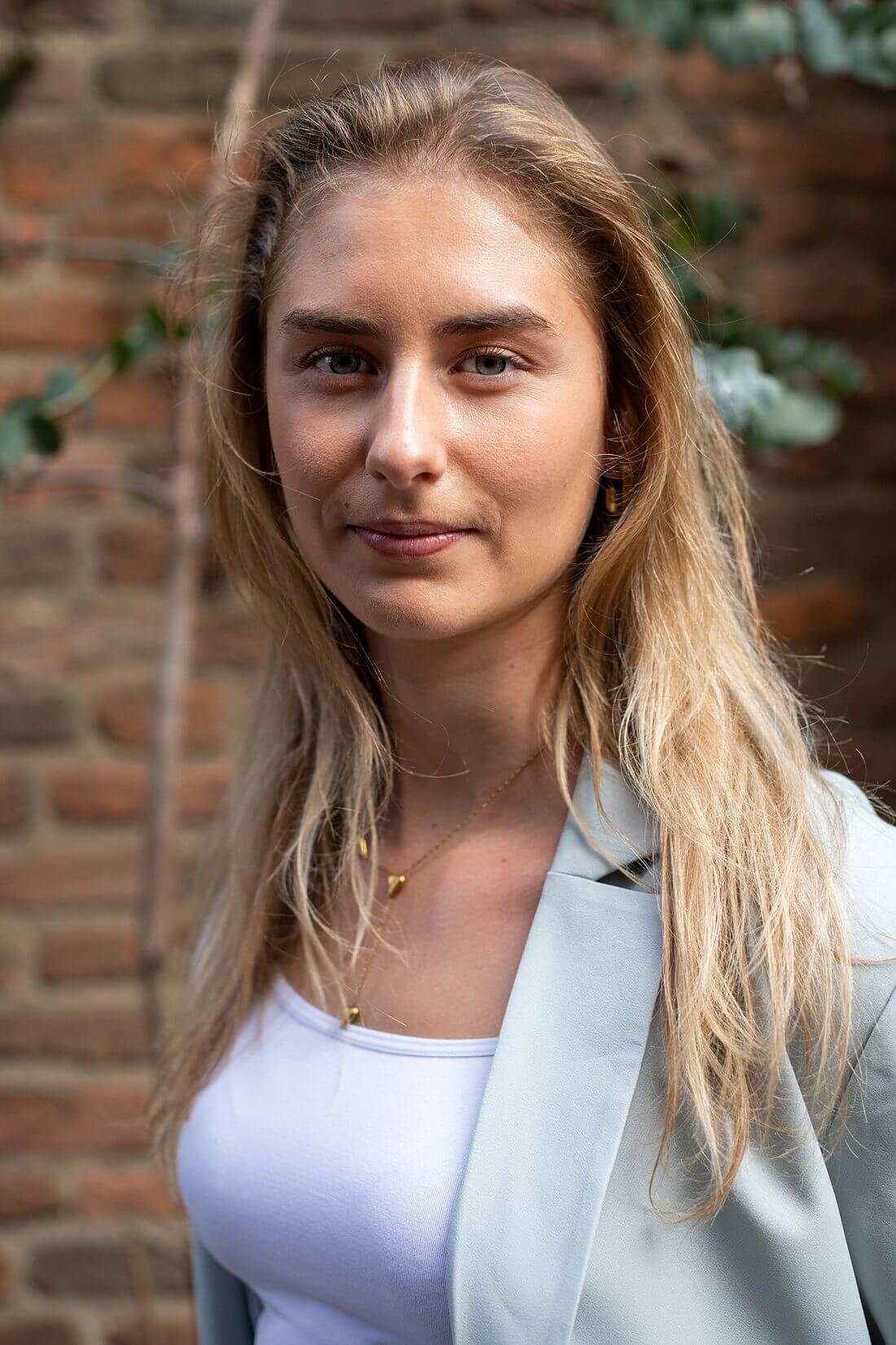 Warm uitnodigend portret van onderneemster Sarah in lichtgrijs pak in Nijmegen.
