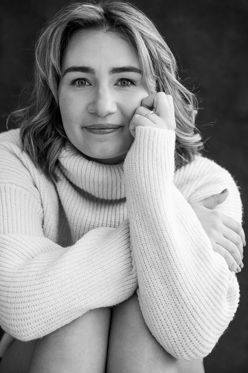 Close-up portret van jonge vrouw met rustige glimlach, zittend op de grond, vrouwenfotografie Breda
