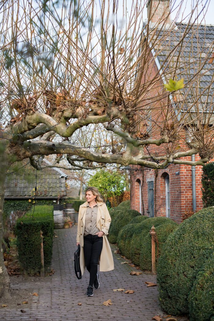 Branding shoot in Rijsbergen van een zakelijke dame met trenchcoat en inspiratietas op weg naar een afspraak.