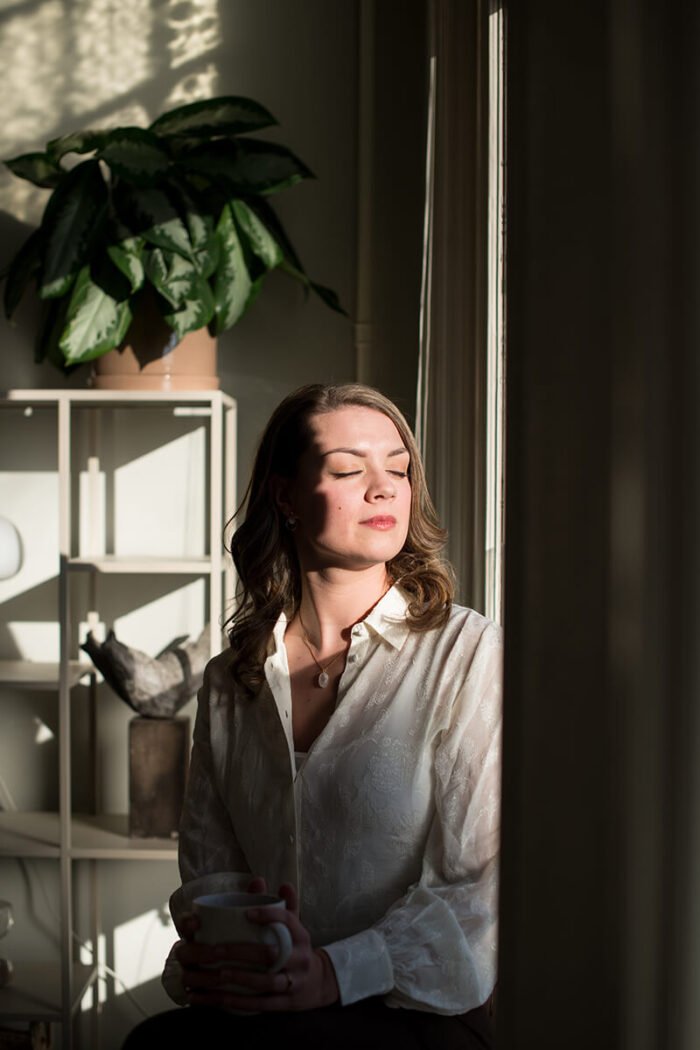 Holistisch psycholoog in haar praktijkruimte in Breda genietend van de ochtendzon.